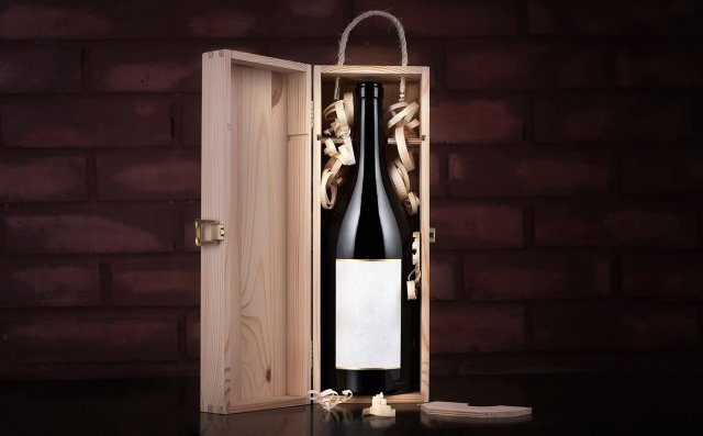 Bottle of wine in a wooden box against a brick wall background.