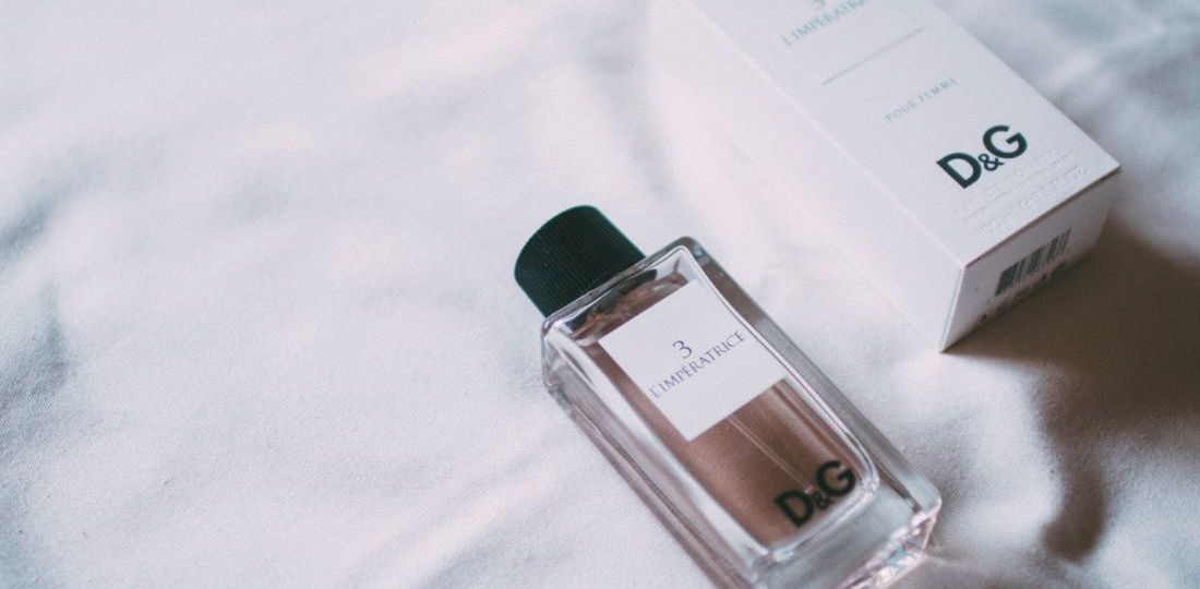 A perfume bottle lying on linen next to its box which is luxury package done correctly.